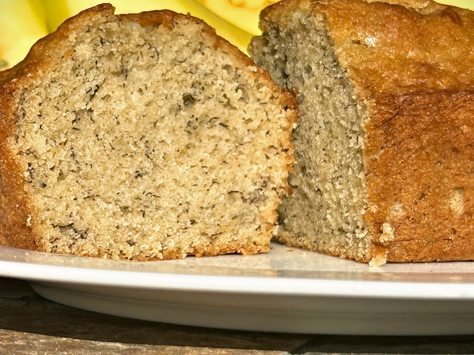 A cut loaf of banana bread on a white plate, showing the crumb