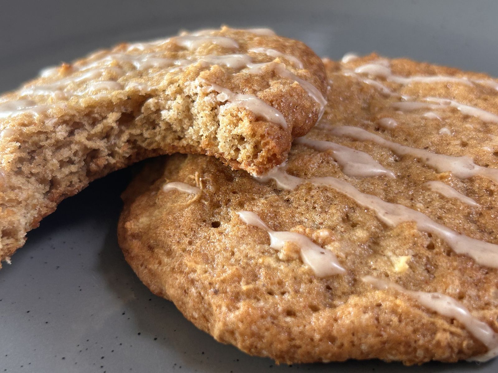 two apple spice cookies on a plate, one with a bite taken out of it
