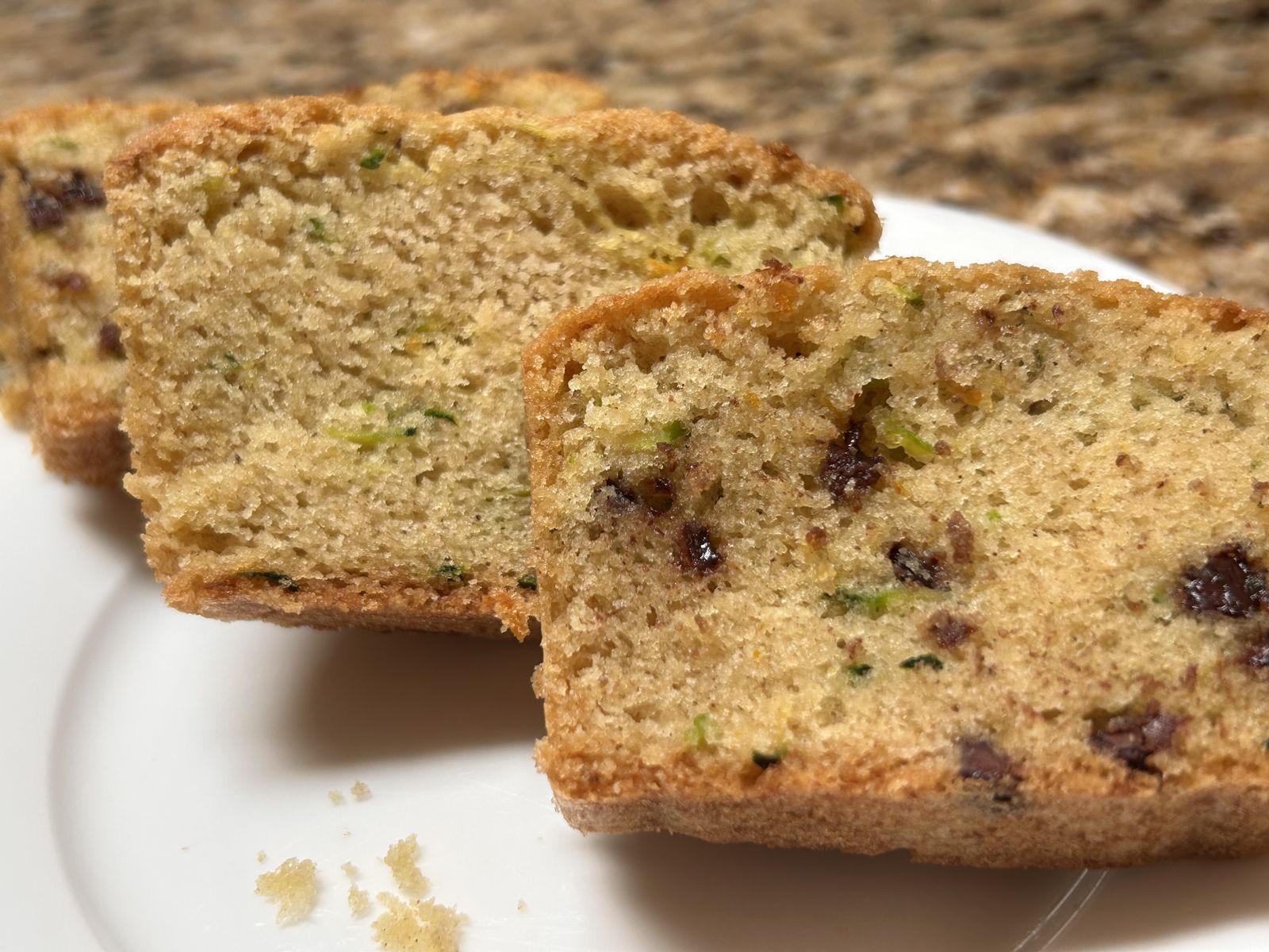 A piece of zucchini bread on top of a piece of chocolate chip zucchini bread on a white plate